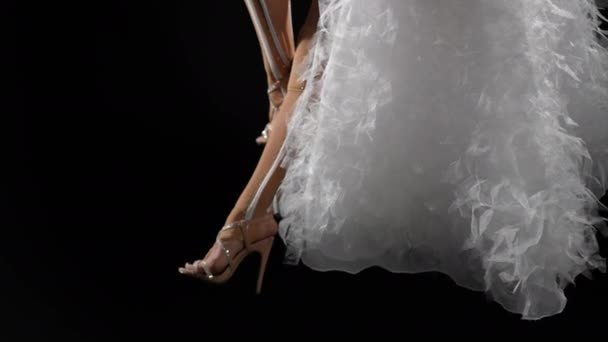 穿着米色服装的纤细女性腿和黑色背景的白色裙子 无法辨认的空中体操运动员挂在空中篮筐上排练 健美操和性能概念 — 图库视频影像