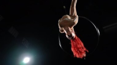 Havada asılı duran gülümseyen güzel bir kadının arka planda siyah ışıkla dönmesi. Kızıl saçlı baştan çıkarıcı Kafkas esnek jimnastikçinin portresi sahnede yavaş çekimde