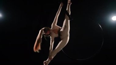 Zayıf, esnek jimnastikçi. Ağır çekimde Fransız ceylanı oynuyor. Kafkasyalı genç bir kadının arka planda ışıkla siyah arka planda kıvrılıp döndüğü geniş açı. Sanat konsepti