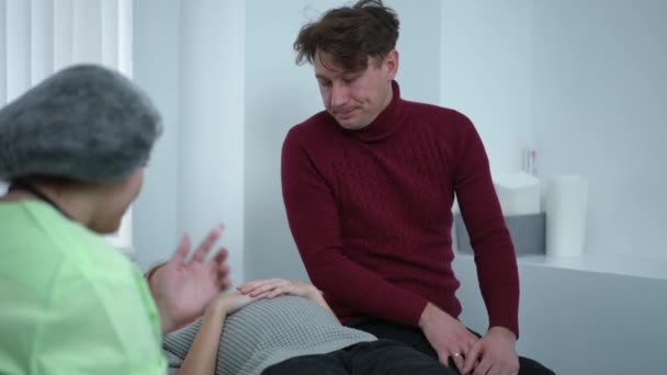 Endişeli Kafkasyalı Bir Adam Hastanede Muayene Koltuğunda Yatan Hamile Bir — Stok video