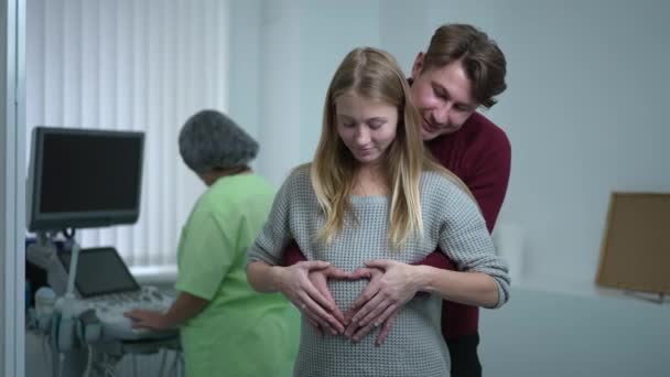 Hamile Karnında Kalp Şeklinde Hareket Eden Mutlu Beyaz Çift Kameraya — Stok video
