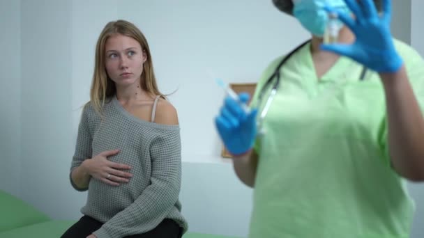 年轻孕妇接触腹部的肖像 作为医生坐在疫苗接种中心 用头孢病毒疫苗填充注射器 高加索人对Covid 19大流行病爆发的预期疫苗接种 — 图库视频影像