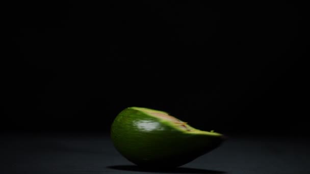 Weibliche Hand Spinnt Halbierte Avocado Vor Schwarzem Hintergrund Auf Dem — Stockvideo