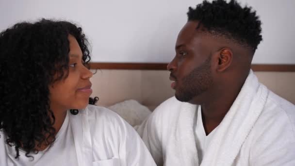 Боковой Вид Любящая Улыбающаяся Афроамериканская Молодая Пара Разговаривает Сидя Кровати — стоковое видео