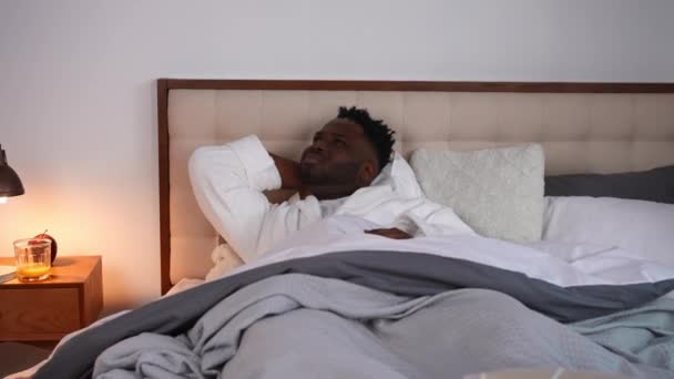 忧心忡忡的非洲裔美国年轻人晚上躺在床上努力入睡 一个忧郁英俊的男人移动枕头失眠的画像 睡眠障碍和疲倦的概念 — 图库视频影像