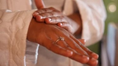 Kapalı alanda avuç içlerine nemlendirici süren yakın plan Afro-Amerikan kadın elleri. Tanımlanamayan hamile bir genç kadın sabahları evdeki tuvalette rutin işler yapıyor.