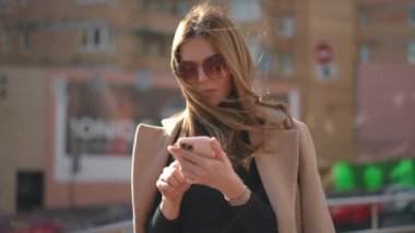 Bin yıllık Kafkasyalı kadın, güneşli şehir şehrinde akıllı telefondan mesajlaşıyor. Sosyal medyada sörf yapan genç, sıska ve güzel bir kadının portresi.