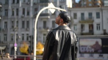 Şehrin sokaklarında gülümseyen mutlu, kendine güvenen eşcinsel bir adamın arka plan portresi. Canlı kameralar sağa sola hareket ederken neşeli beyaz LGBTQ çalışanı şehir merkezine hayran.