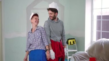 Yeni evde el ele tutuşup poz veren kağıt şapkalı neşeli çifte yakınlaş. Canlı kamera, gülümseyen beyaz adam ve kadının kameraya bakıp gülümsemesine yaklaşıyor.