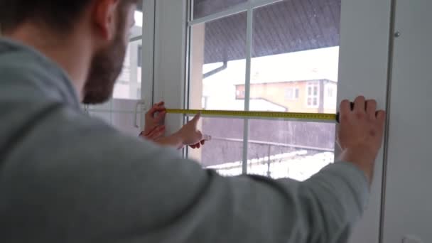 全神贯注的男人在屋里用尺子测量窗户 与女人交谈 重点讨论新住房重建和维修问题的白人夫妻 — 图库视频影像
