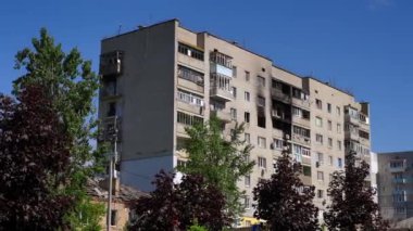 Canlı kamera, Kyiv Ukrayna 'daki bombalanmış çok katlı binayı göstererek soldan sağa hareket ediyor. Yıkılmış evin geniş açılı görüntüsü, arka planda mavi yaz gökyüzünün gün ışığında.