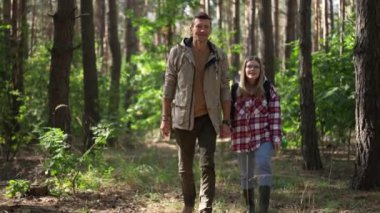 Ormanda ağır çekimde yürüyen mutlu ve sevgi dolu bir çiftin portresi. Gülümseyen beyaz bir adam ve kadın ormanda doğa yürüyüşü yapıyorlar. Macera konsepti