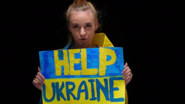 勇敢而自信的乌克兰女人在镜头前说话的画像 帮助乌克兰 美丽的身材苗条的年轻女子 身披黑底 高举横幅 要求支援和防卫 — 图库视频影像