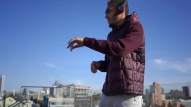 Sağdan sola dönen, kulaklıklı neşeli, Afro-Amerikan bir adam çatıda dans ederek şarkı söylüyor. Neşeli, kaygısız yakışıklı adam şehir merkezinde hafta sonları eğleniyor.