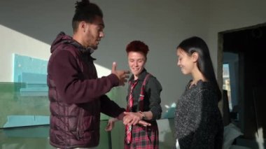 Neşeli arkadaşlar ağır çekimde el ele tutuşup baş parmaklarını kaldırarak gülüyorlar. Afro-Amerikan Asyalı ve Kafkasyalı kadın ve erkek inşaatta eğleniyor.