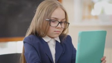 İnternette tablet üzerinde sörf yapan konsantre liseli kız sınıftaki masada oturuyor. Kafkas öğrencilerin okulda kapalı alanda öğrendiklerinin portresi. Yaşam tarzı ve eğitim kavramı