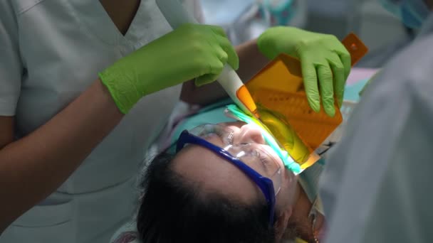 Dişçi Koltuğundaki Beyaz Kadın Tanınmayan Bir Doktor Hemşire Ile Ultraviyole — Stok video