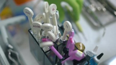 Arka plandaki araçları kullanarak bulanık dişçi eliyle işaretli restoratif bileşik yakın çekim seti. Kapalı alandaki hastanede diş tedavisi için profesyonel malzemeler. Diş sağlığı ve ilaç