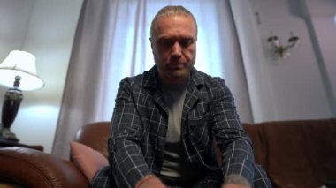 Web camera POV of concentrated confident man typing on laptop keyboard looking at camera. Portrait of handsome Caucasian male freelancer in pajamas messaging online sitting on couch at home