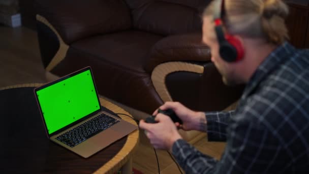Uomo Assorbito Cuffie Gioco Computer Portatile Schermo Verde Utilizzando Controller — Video Stock