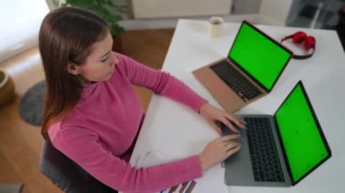 Aşırı yorgun Kafkasyalı kadın esneyerek yeşil ekran laptoplarıyla masada kestiriyor. Yorgun kadın serbest çalışanın internetten mesajlaşarak uykuya daldığı yüksek açılı görüntü. Çoklu görev ve yorgunluk