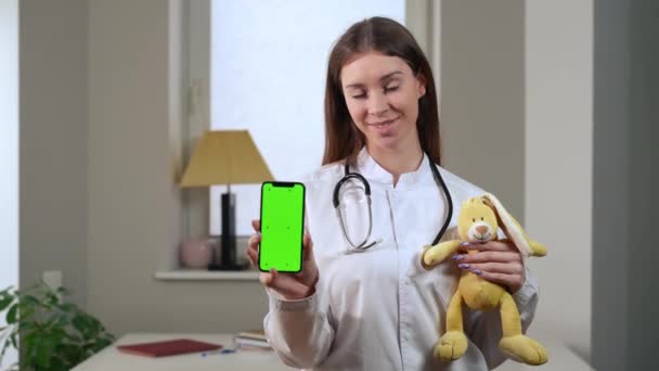 Medium Shot Portrait Smiling Pediatrician Toy Showing Web App Green — Stockvideo