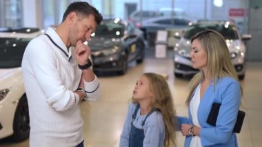 Sevimli bir kız, ailelerinden lüks bir araba satın almalarını istiyor. Mutluluk dolu, mutlu, beyaz bir kız, anne ve babasıyla birlikte galeride araç seçiyor. Başarı ve yaşam tarzı