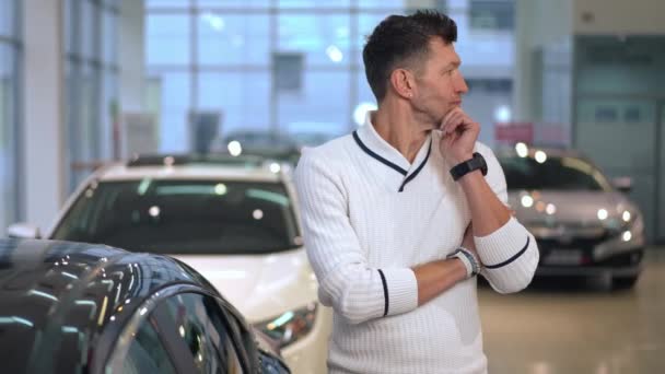 Thoughtful Caucasian Wealthy Man Standing Car Dealership Choosing New Vehicle — Video