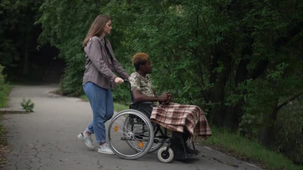 Caucasian Girlfriend Pushing Wheelchair African American Boyfriend Lake Pointing Talking — Stock video