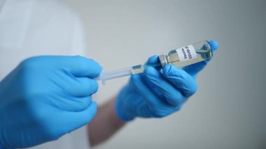 Close-up doctor hands in gloves filling syringe with Covid-19 vaccine in vaccination center. Unrecognizable Caucasian man preparing coronavirus vaccine jab in hospital medical clinic. Pandemic concept