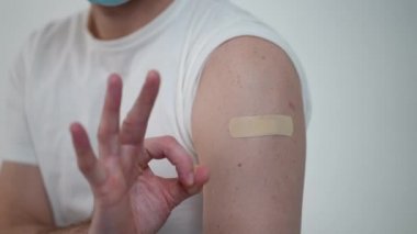 Yakın çekim erkek eli, Covid-19 aşısından sonra sağlık bandıyla omuz hizasında. Tanımlanamayan yetişkin bir beyaz adam hastanede aşı oluyor. Hastalık önleme kavramı