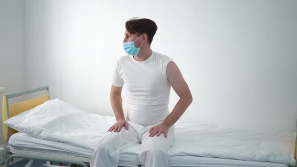 Anxious Worried Caucasian Man Coronavirus Face Mask Sitting Bed Hospital — 图库视频影像