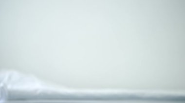 Hastane koğuşunda beyaz yatak. Beyaz tekerlekli sandalyeli, tanınmaz halde. Pencereden dışarı bakan felçli hasta, hareket edebilirlik cihazıyla geziyor. Hastalık ve umut