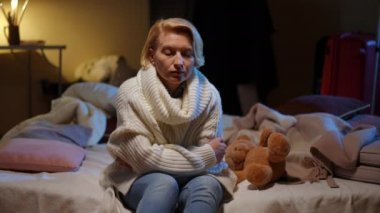 Anxious stressed woman sitting in bomb shelter listening to bombardment explosions. Portrait of worried sad Ukrainian lady hiding waiting for the end of air raid alert warning in war zone