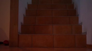 Red lamp flashing during air raid alert warning as unrecognizable woman and girl walking downstairs to bomb shelter. Worried Ukrainian mother and daughter hiding from bombardment in war zone