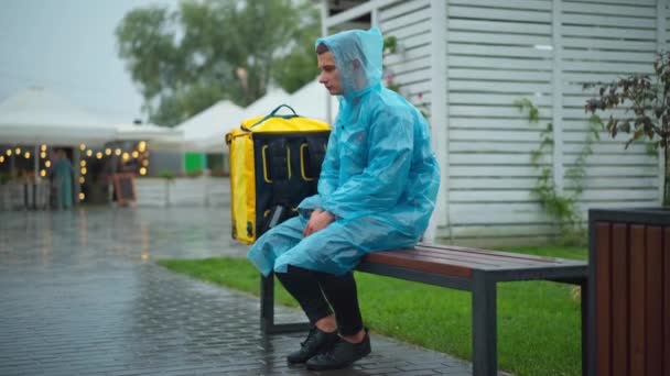 Wide Shot Portrait Tired Sad Courier Rain Coat Sitting Bench — Vídeo de Stock