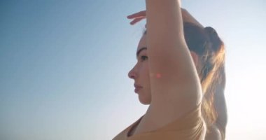 Live camera follows graceful woman bending in sunrays at background of sea at sunrise. Elegant Caucasian ballet dancer rehearsing outdoors at dawn in slow motion. Cinema 4k ProRes HQ
