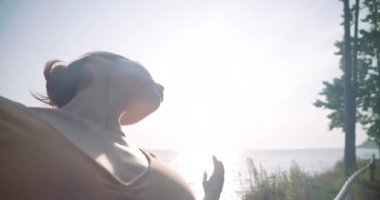 Side view confident slim woman in sunshine moving hands in sunrays in slow motion looking away. Graceful talented Caucasian ballerina performing outdoors. Cinema 4k ProRes HQ