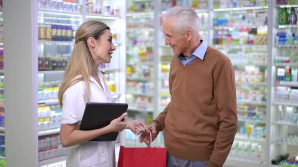 Side View Expert Pharmacist Passing Shopping Bag Medications Senior Client — ストック動画