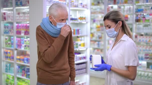 Профессиональный Фармацевт Коронавирусной Маске Рекомендует Таблетки Пожилого Человека Кашляющего Стоя — стоковое видео