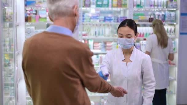 Young Asian Woman Taking Temperature Caucasian Senior Man Pharmacy Entrance — Stockvideo