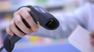 Close-up scanning bar code of pills with scanner in pharmacy indoors in slow motion. Unrecognizable pharmacist selling medication in drugstore. Service and pharmaceutical industry concept