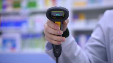 Front view close-up bar code reader in female hand with red light flashing. Unrecognizable woman pharmacist scanning QR code in drugstore in slow motion