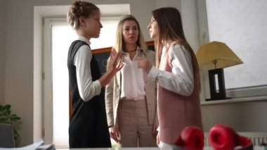 Teenage classmates arguing as teacher calming down angry students talking. Dissatisfied Caucasian schoolgirls and caring tutor standing in classroom in school. Conflict management concept
