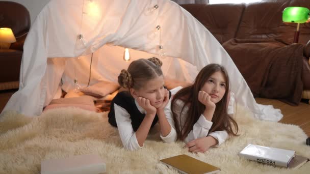 Two Charming Teen Girls Lying Tent Living Room Books Talking — Vídeo de stock