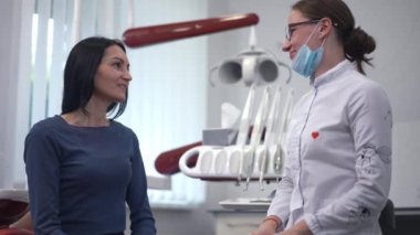 Satisfied patient and smiling doctor shaking hands in slow motion in hospital indoors. Portrait of confident expert doctor and Caucasian woman handshaking after appointment in medical clinic