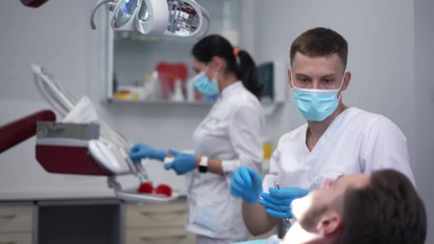 Focused Expert Dentist Adjusting Dental Lamp Examining Patient Oral Cavity — Wideo stockowe