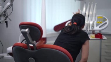 Back view woman cleaning dental equipment in slow motion sitting in hospital indoors. Professional confident Caucasian dentist assistant preparing tools for visit indoors