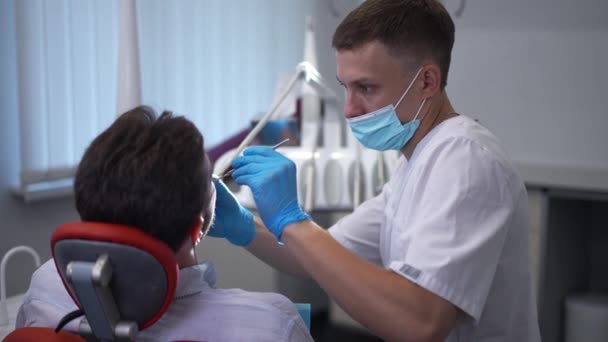 Side View Concentrated Smart Dentist Using Equipment Treating Ill Teeth — Stockvideo