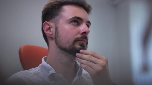 Close Thoughtful Handsome Man Rubbing Beard Sitting Dental Chair Waiting — Wideo stockowe